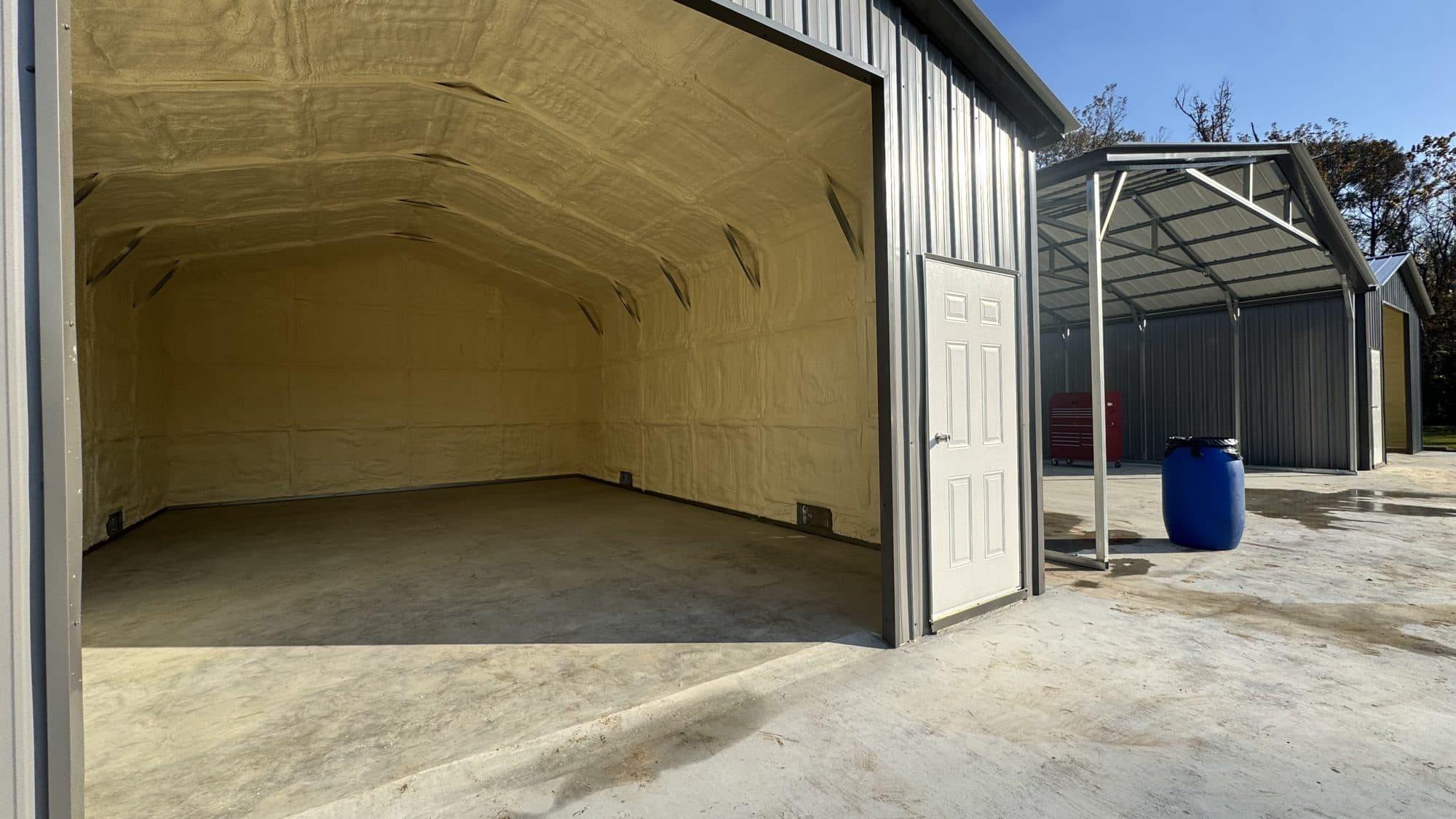 Metal building interior featuring yellow spray foam insulation on the walls and arched ceiling.