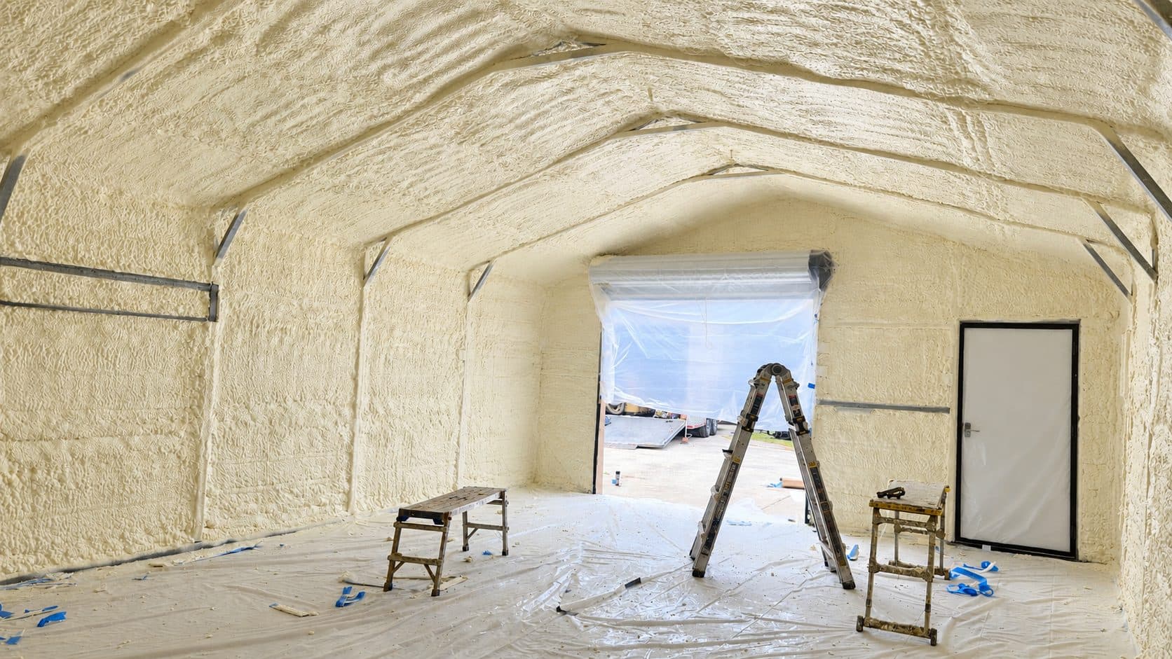 Interior of a garage with walls and ceiling completely covered in thick spray foam insulation.