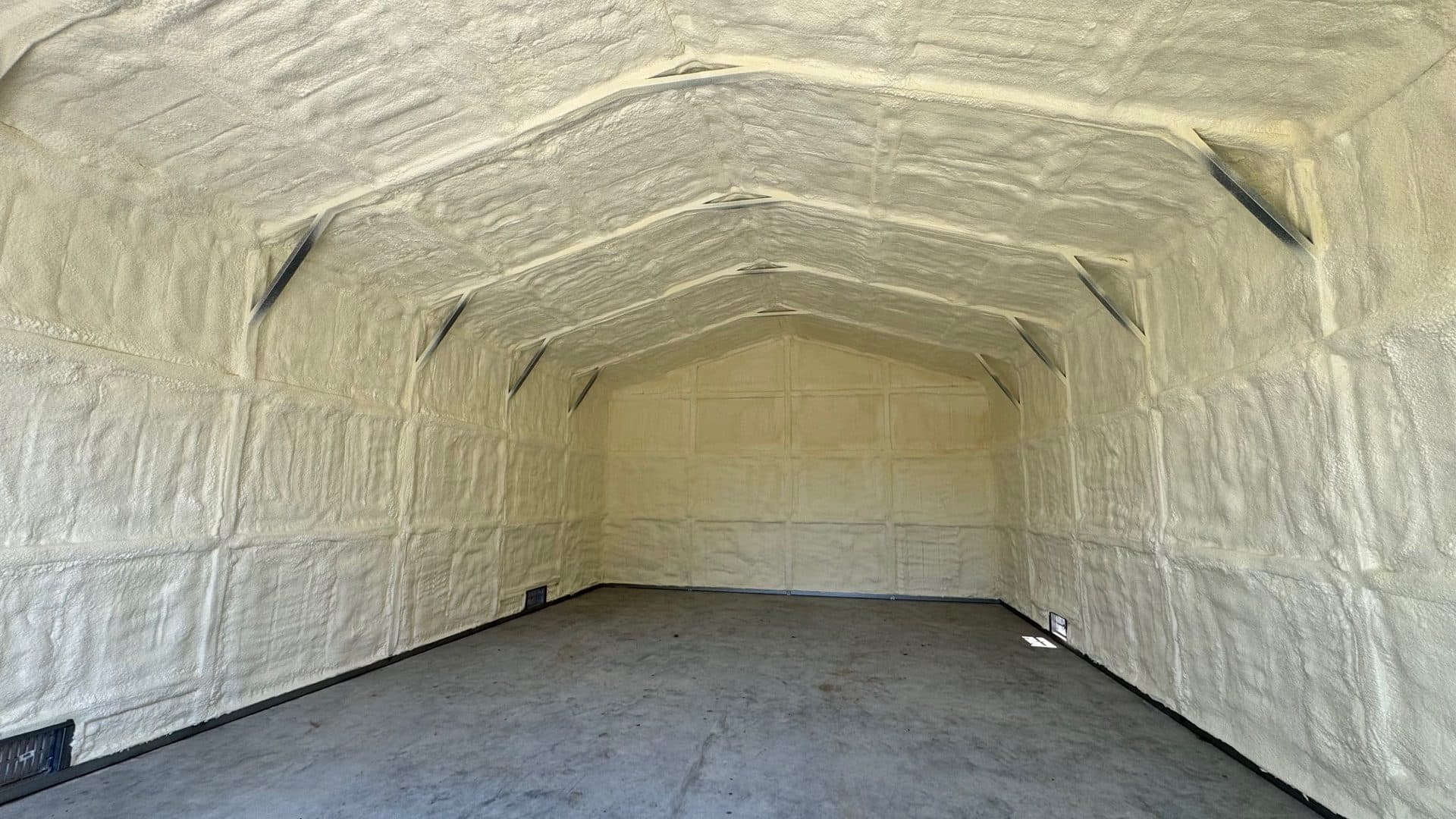 Interior of a metal building with walls and ceiling completely covered in spray foam insulation.