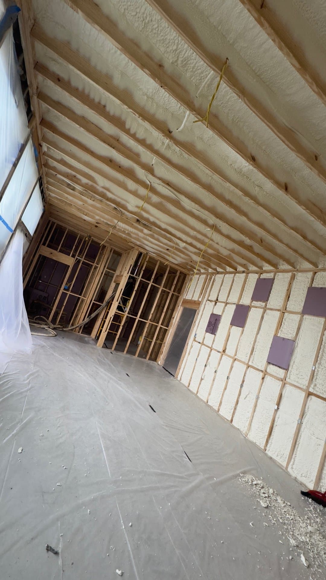 Spray foam insulation applied between wooden wall and ceiling framing in a building under construction.